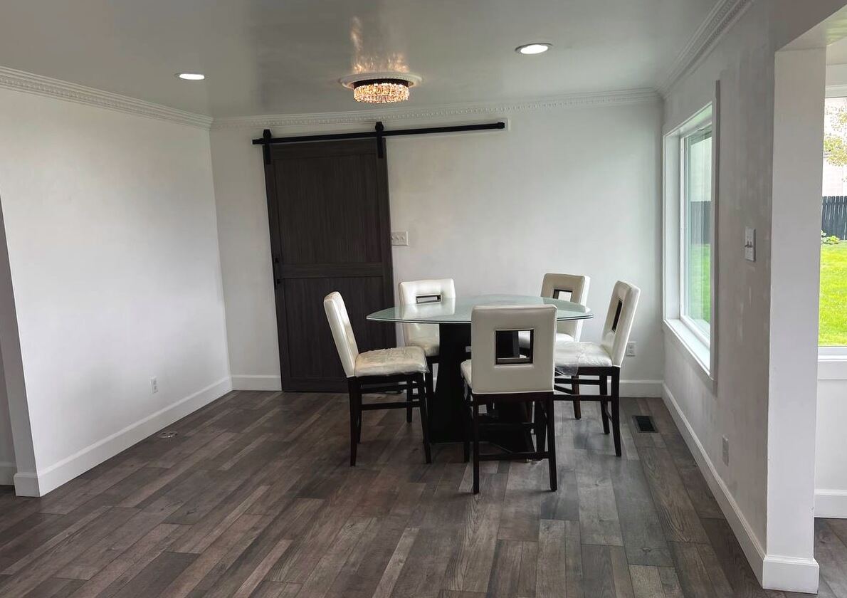 Open middle room with a sliding barn door, crown molding and a window onto the back lawn
