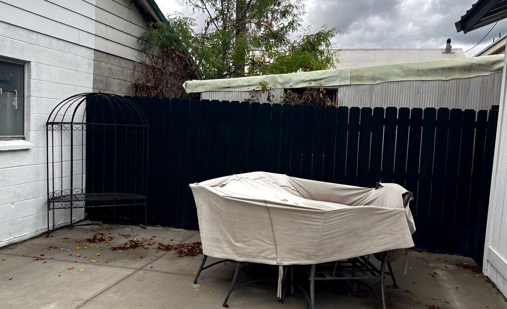 Private fenced concrete patio between the garage and the rear outbuilding