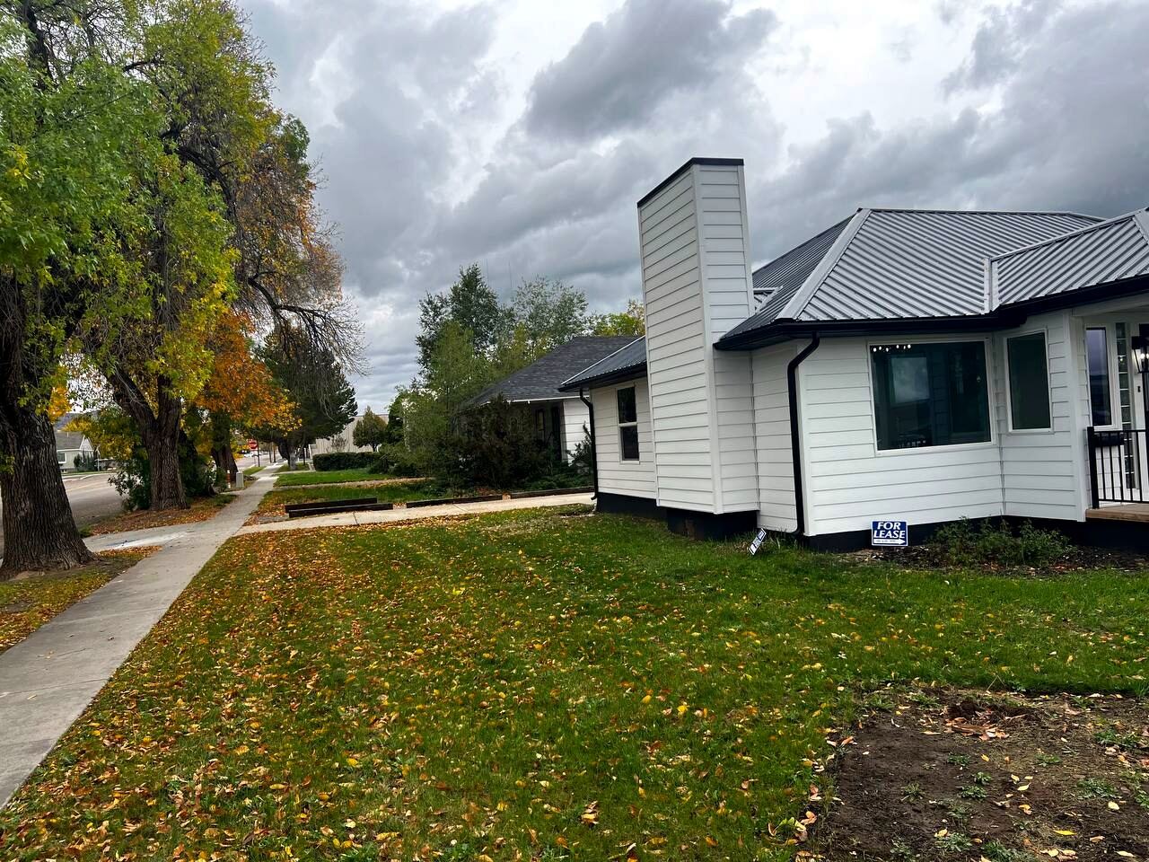 Tree-lined side street with sidewalk running past the property